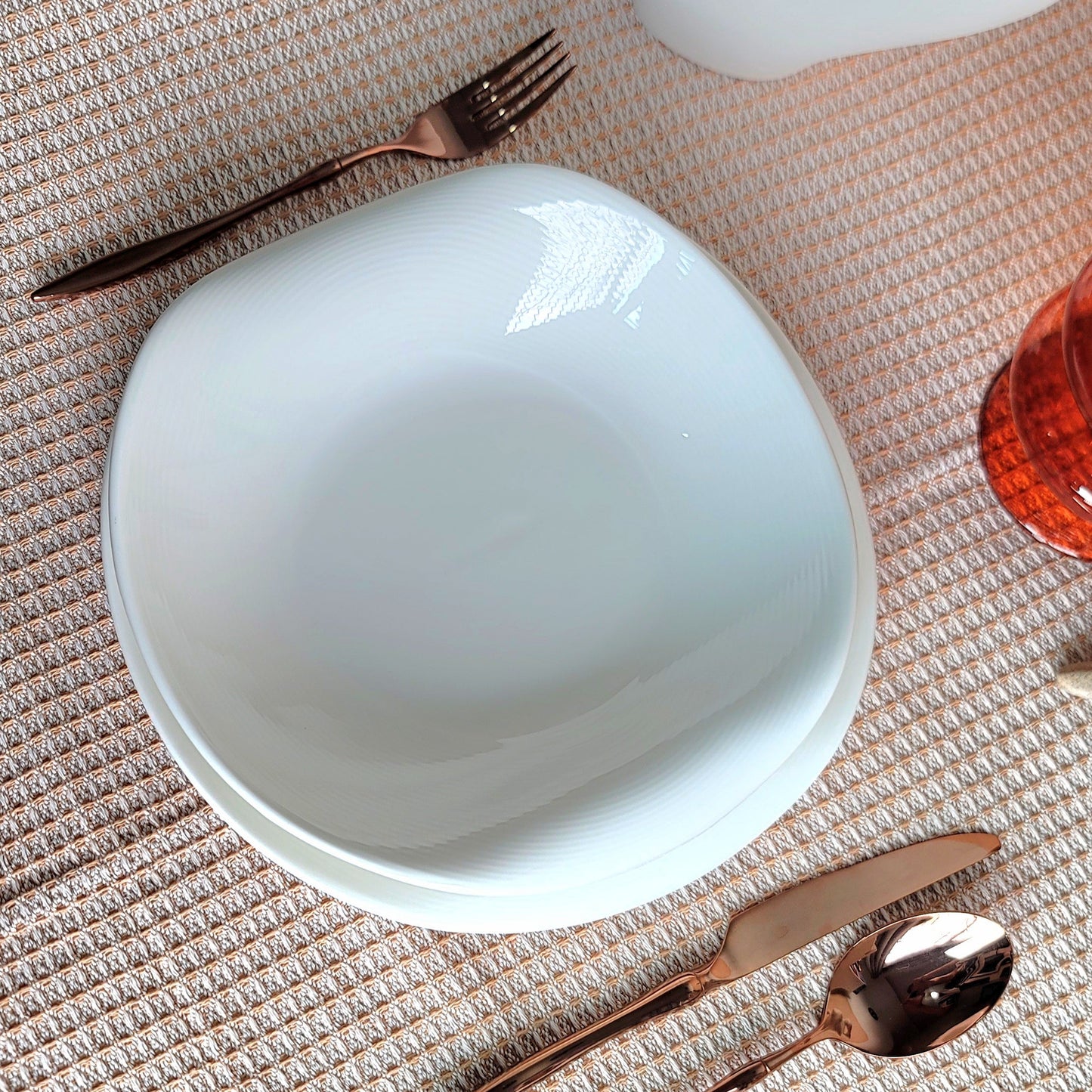 White bowl with a pair of tongs on a textured surface