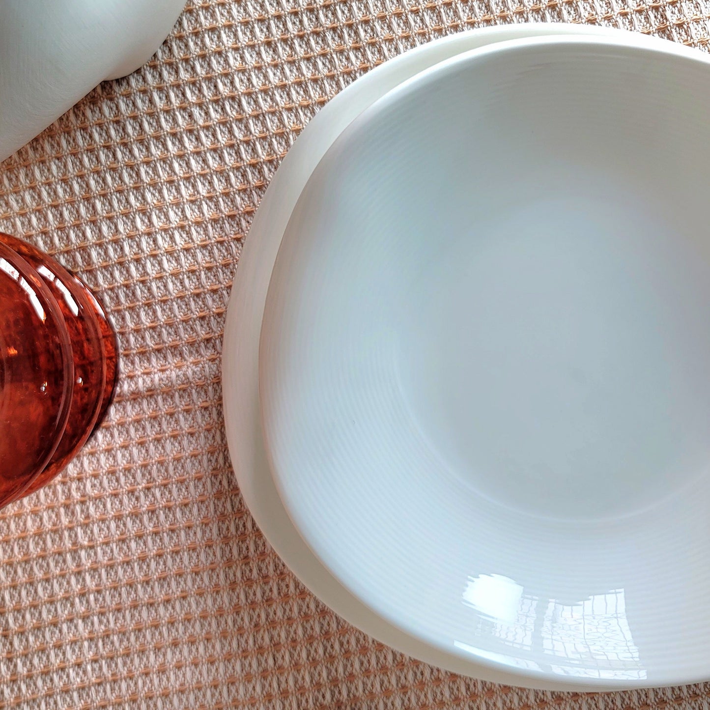 White ceramic bowl on a textured surface with a small brown object and beige fabric.