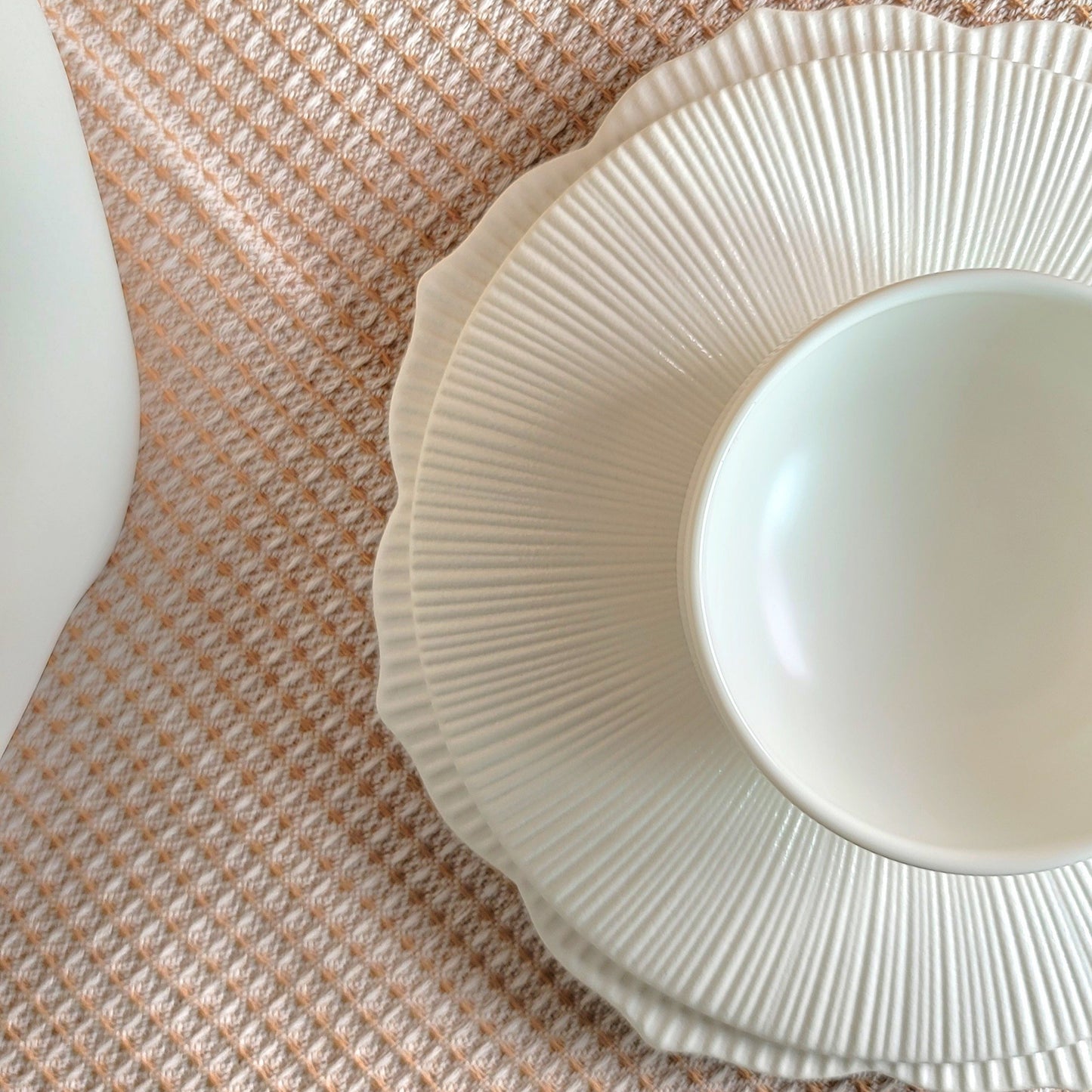 White ceramic plate with textured rim on a woven mat