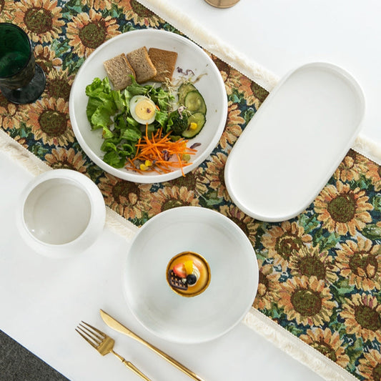 Dinner setup with white bowls, a floral placemat, and gold cutlery on a textured surface.