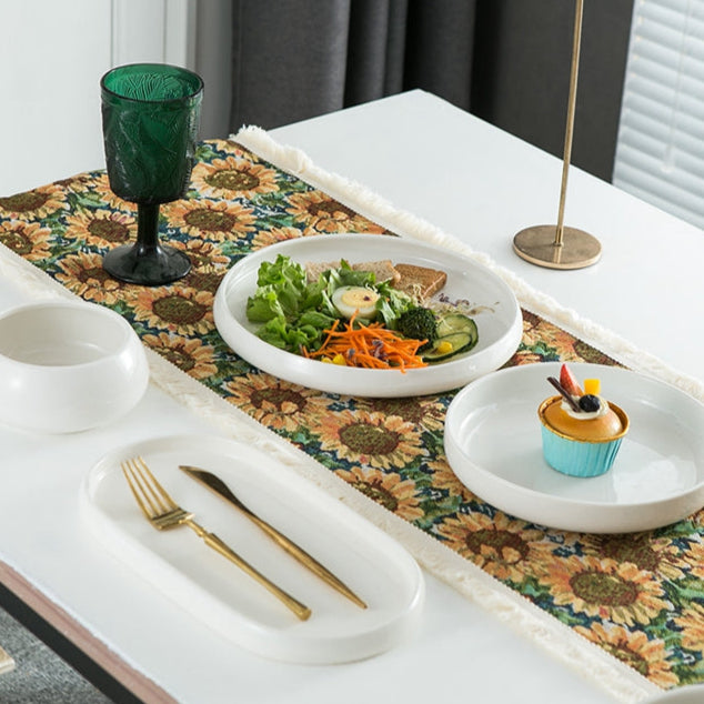 Table setting with plates of food, a cup, and cutlery on a floral table runner.