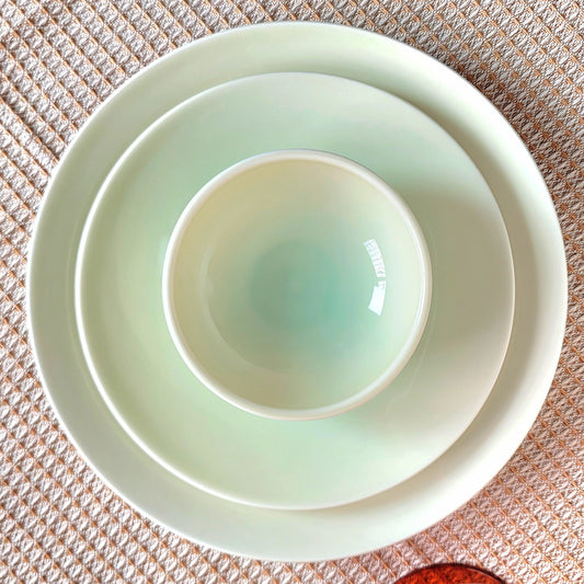 Set of light green ceramic bowls on a textured surface