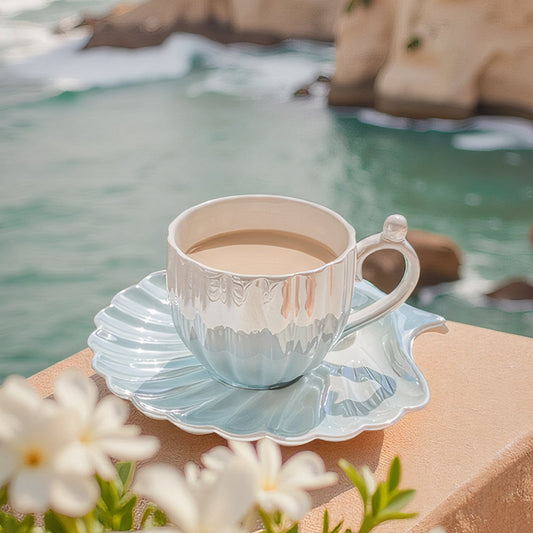 Designed to mimic the graceful curves of a seashell, each piece boasts a delicate iridescent finish that catches the light, evoking the shimmer of ocean pearls. The sculpted handle features a charming pearl-like accent,