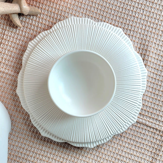 White ceramic bowl with textured rim on a textured surface