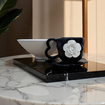 Black mug with white flower design on a marble table